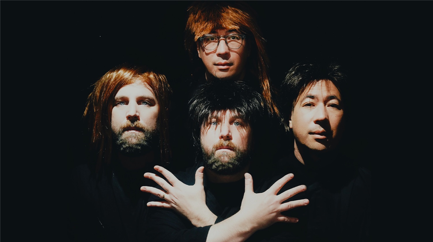 Four men posing dramatically in wigs with a dark background, parodying the iconic "Bohemian Rhapsody" Queen album cover.